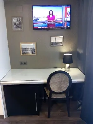 a desk with a television on a wall with a chair at Moderno in Barcelona