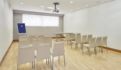 a conference room with chairs and a table and a screen at NH Barcelona Stadium in Barcelona