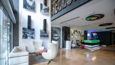 a lobby with white chairs and a sign on the wall at Evenia Rocafort in Barcelona
