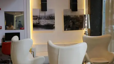 a living room with white chairs and paintings on the wall at Evenia Rocafort in Barcelona