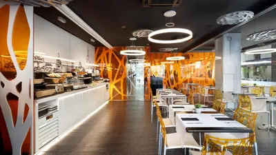 a restaurant with tables and chairs and a kitchen at Evenia Rossello in Barcelona