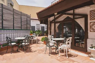 a patio with tables and chairs outside of a building at Mesón Castilla Atiram Hotels in Barcelona