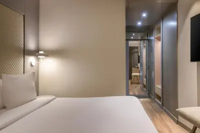 a bedroom with a large white bed and a corridor at AC Hotel Som by Marriott in Hospitalet de Llobregat
