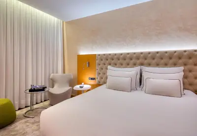 a bedroom with a large white bed and a chair at Sansi Pedralbes in Barcelona