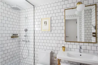 a white tiled bathroom with a sink and a mirror at Hotel Midmost by Majestic Hotel Group in Barcelona