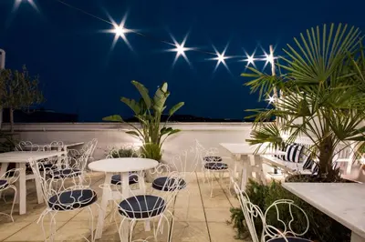 a rooftop patio with tables and chairs at night at Hotel Midmost by Majestic Hotel Group in Barcelona