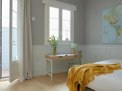 a bedroom with a bed and a desk and windows at Casa Cosi Patio 1 in Barcelona