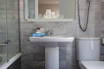 a bathroom with a sink and a toilet and a mirror at BCN Urbaness Hotels Del Comte in Barcelona