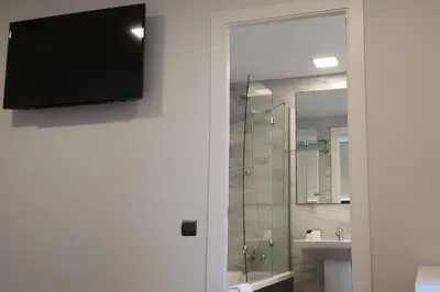 a bathroom with a shower and a television on a wall at BCN Urbaness Hotels Del Comte in Barcelona
