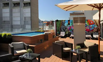 a patio with a pool and chairs and an umbrella at Sercotel Amister Art Hotel Barcelona in Barcelona