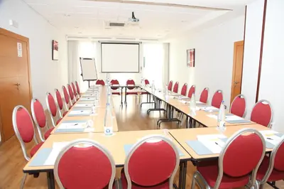 a conference room with long tables and red chairs at Travelodge Barcelona del Vallés in Barbera del Valles
