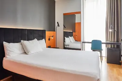 a bedroom with a large white bed with a blue chair at Silken Sant Gervasi in Barcelona