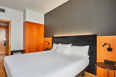 a bedroom with a large white bed with a black headboard at Silken Sant Gervasi in Barcelona