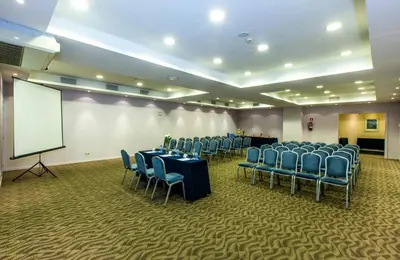 a conference room with tables and chairs and a white screen at Leonardo Hotel Barcelona Gran Via in Barcelona