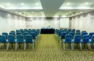 a conference room with blue chairs and a screen at Leonardo Hotel Barcelona Gran Via in Barcelona