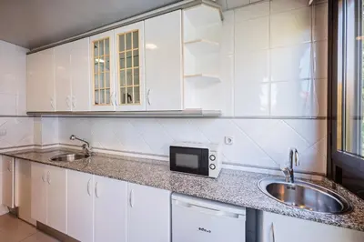 a kitchen with white cabinets and a sink and a microwave at Aparthotel Napols - Abapart in Barcelona