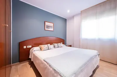 a bedroom with a large bed with a blue wall at Aparthotel Napols - Abapart in Barcelona