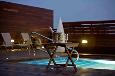 a table next to a pool with a tea pot on it at Hotel Lleó in Barcelona