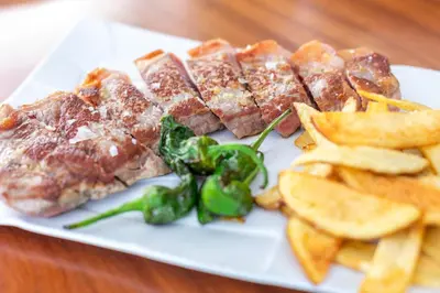 a plate of food with meat and vegetables and chips at Abba Sants in Barcelona