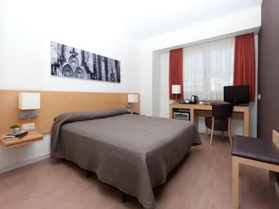 a bedroom with a bed and a desk with a computer at Hotel Sagrada Familia in Barcelona