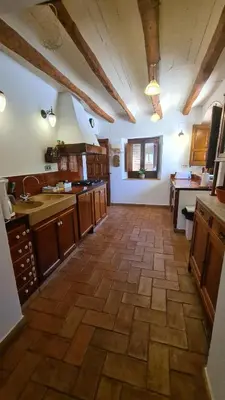 a large kitchen with wooden cabinets and a tile floor at Cal Colina - Karaktervol landhuis met privé zwembad in Pacs del Penedes