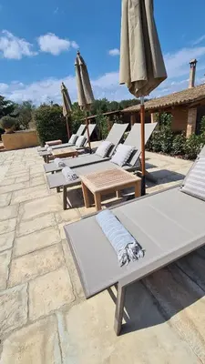 a row of lounge chairs and umbrellas on a patio at Cal Colina - Karaktervol landhuis met privé zwembad in Pacs del Penedes