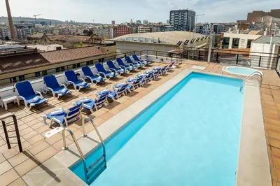 a pool on the roof of a building with chairs at Sunotel Aston in Barcelona
