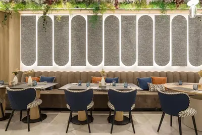 a restaurant with tables and chairs in front of a wall at Ilunion Les Corts Spa in Barcelona