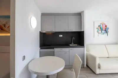a small kitchen with a white table and a couch at Aparthotel Miami Park in Calella