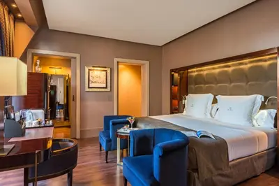 a hotel room with a large bed and blue chairs at Hotel Casa Fuster G.L Monumento in Barcelona