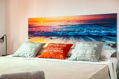 a bed with two pillows and a painting of the beach at Dream House in Badalona