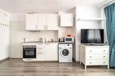a kitchen with white cabinets and a washer and dryer at Dream House in Badalona