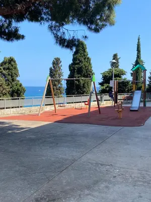 a playground with two swings and the ocean in the background at 3 BDRM APART NEAR THE SEA! GREAT FOR KIDS! in Arenys de Mar