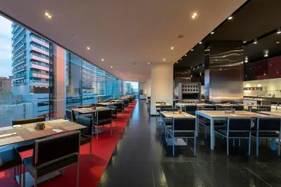 a restaurant with tables and chairs in a building at Leonardo Royal Hotel Barcelona Forum in Barcelona