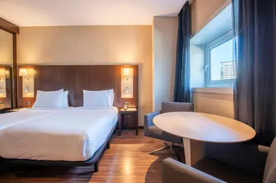 a hotel room with a large bed and a table at Leonardo Royal Hotel Barcelona Forum in Barcelona