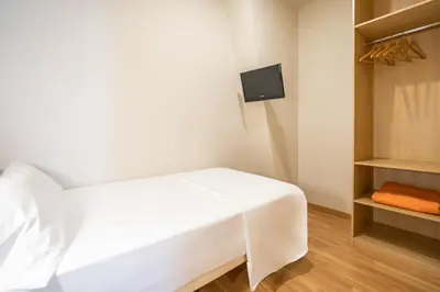 a white bed in a room with a tv at Hotel Glòries in Barcelona