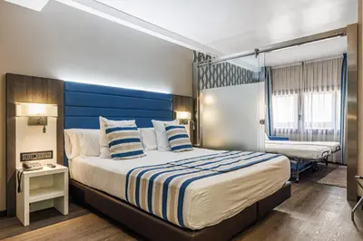 a hotel room with a bed with a blue headboard at Hotel Ronda Lesseps in Barcelona