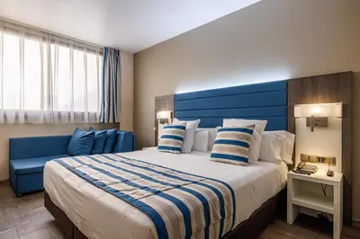 a hotel room with a large bed with a blue headboard at Hotel Ronda Lesseps in Barcelona