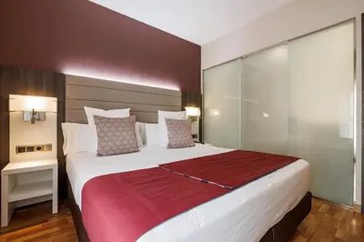 a bedroom with a large bed with a red blanket at Hotel Ronda Lesseps in Barcelona