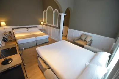 a bedroom with two beds and a couch and a desk at Hotel Granvia in Barcelona