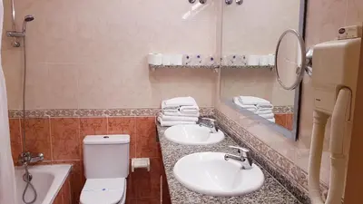 a bathroom with two sinks and a toilet and a mirror at Hotel Piccadilly Sitges in Sitges