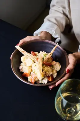a person holding a sandwich in a container on a table at Gran Hotel Havana 4Sup by Escampa Hotels in Barcelona