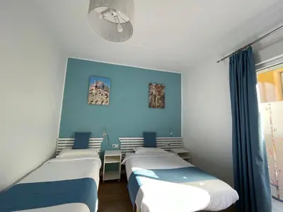 a room with four beds against a blue wall at Pensión Bertolín in Barcelona
