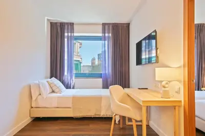 a bedroom with a bed and a desk and a window at Hotel Acta Azul Barcelona in Barcelona