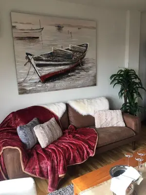 a living room with a couch and a painting of a boat at La Pastora Lux cerca de Barcelona in Gavà