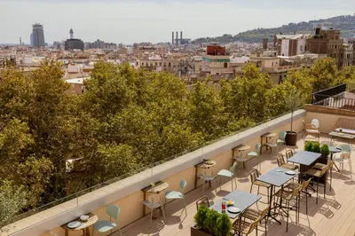a balcony with tables and chairs and a view of a city at Líbere Barcelona Sant Antoni in Barcelona