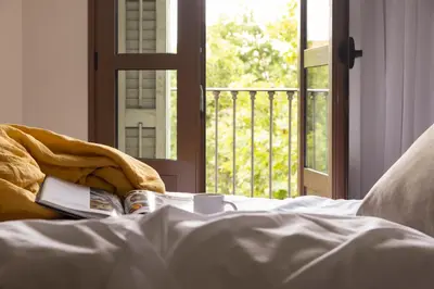 a bed with a book on it with a window at Líbere Barcelona Sant Antoni in Barcelona