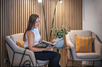 a woman sitting in a chair reading a book at Hotel SERHS Del Port in Barcelona