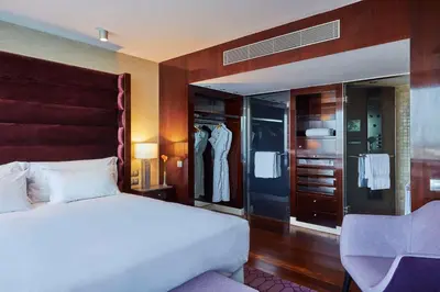 a bedroom with a bed and a dressing room at Hyatt Regency Barcelona Tower in Hospitalet de Llobregat