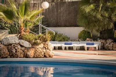a swimming pool with lounge chairs and palm trees at htop Olympic #htopEnjoy in Calella